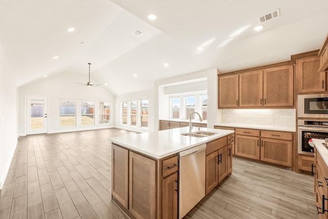 kitchen with brown cabinetry, visible vents, stainless steel appliances, and a sink