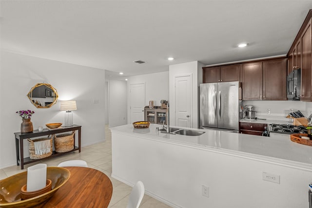 kitchen featuring sink, stainless steel fridge, light tile patterned floors, dark brown cabinets, and stove