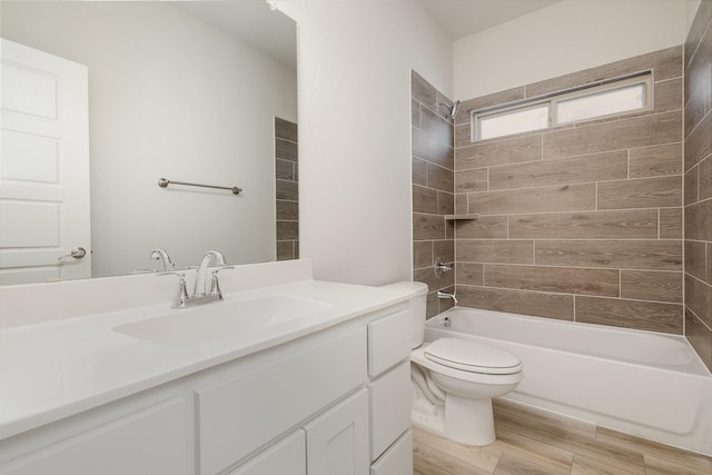 full bathroom featuring tiled shower / bath combo, toilet, wood-type flooring, and vanity