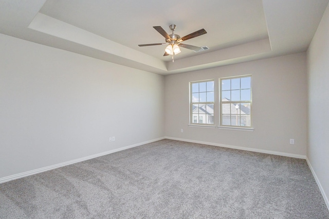 carpeted spare room featuring a raised ceiling and ceiling fan