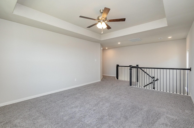 spare room with ceiling fan, carpet floors, and a tray ceiling