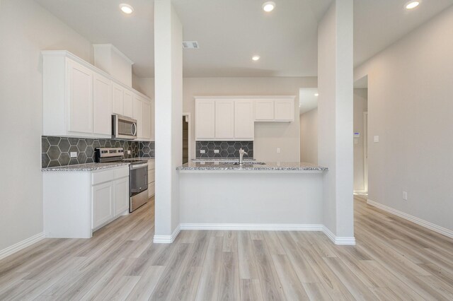 kitchen featuring white cabinets, stainless steel appliances, light hardwood / wood-style flooring, and light stone countertops