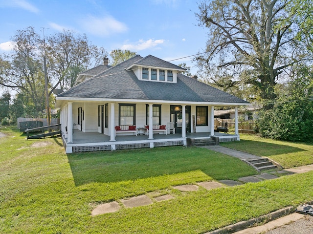 farmhouse featuring a porch, roof with shingles, a chimney, and a front lawn