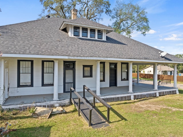 view of front of home featuring a shingled roof, a chimney, a porch, and a front yard