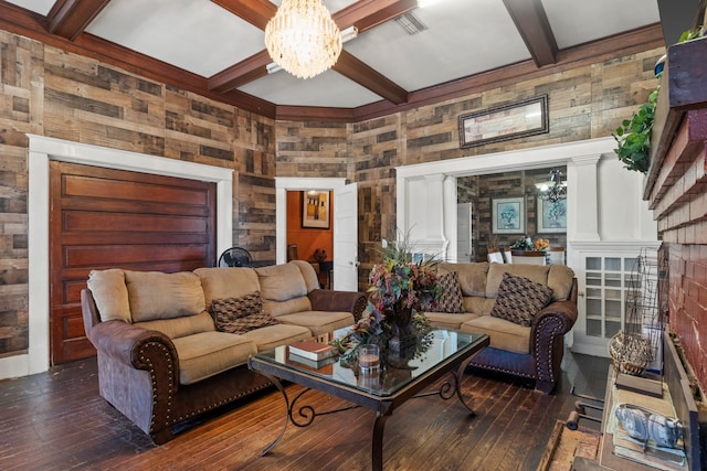 living room with an inviting chandelier, dark wood-style flooring, beamed ceiling, and wood walls