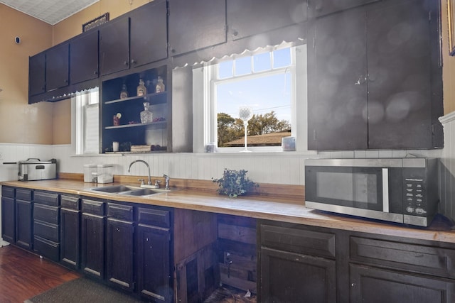 kitchen featuring blue cabinetry, wood counters, stainless steel microwave, and a sink