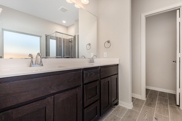 bathroom with hardwood / wood-style floors, vanity, and a shower with door