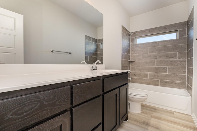 full bathroom with vanity, hardwood / wood-style floors, tiled shower / bath combo, and toilet