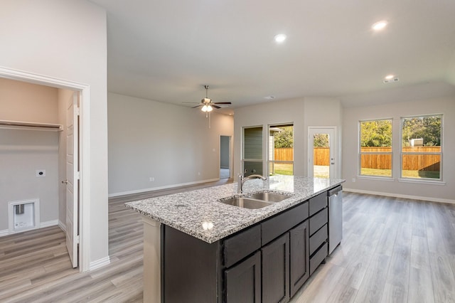 kitchen with ceiling fan, sink, light hardwood / wood-style flooring, stainless steel dishwasher, and an island with sink