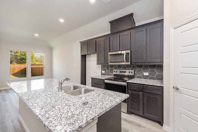 kitchen featuring appliances with stainless steel finishes, an island with sink, light hardwood / wood-style flooring, and sink