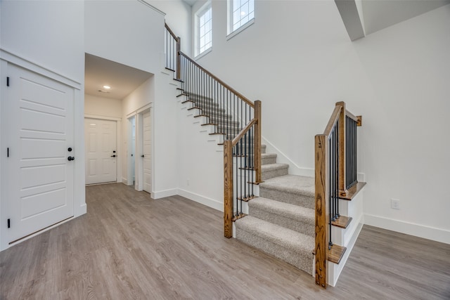 stairs featuring a towering ceiling and wood-type flooring