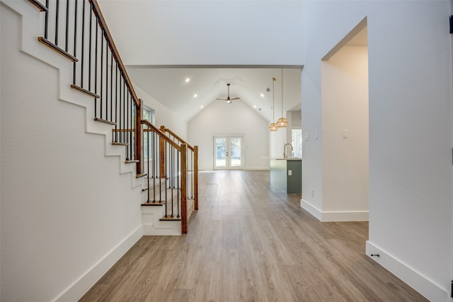 interior space with french doors, ceiling fan, sink, light hardwood / wood-style floors, and lofted ceiling