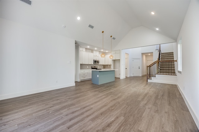 unfurnished living room with light hardwood / wood-style flooring, high vaulted ceiling, and sink