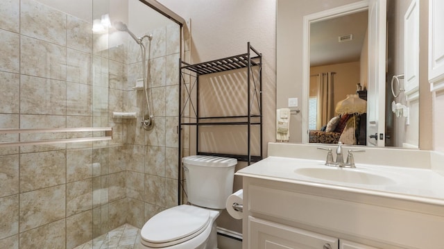 bathroom with tiled shower, vanity, and toilet