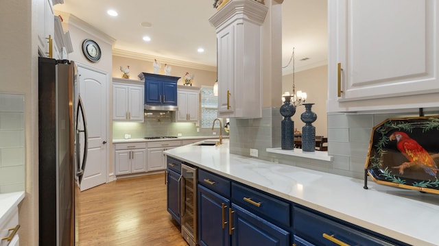 kitchen with sink, blue cabinets, backsplash, stainless steel fridge, and white cabinets