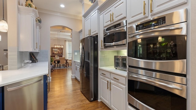 kitchen featuring decorative backsplash, white cabinetry, appliances with stainless steel finishes, and light hardwood / wood-style flooring