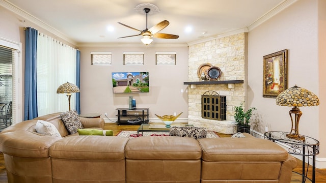 living room featuring a stone fireplace, ceiling fan, hardwood / wood-style floors, and ornamental molding