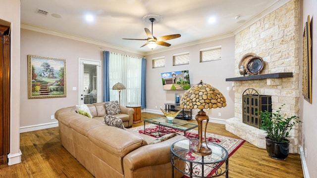 living room featuring a stone fireplace, crown molding, ceiling fan, and hardwood / wood-style flooring