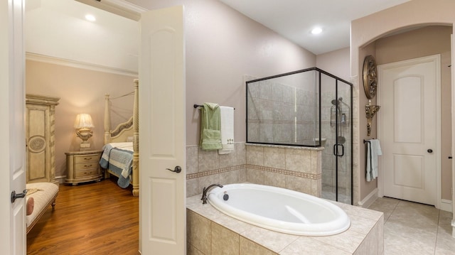 bathroom with plus walk in shower, hardwood / wood-style flooring, and crown molding