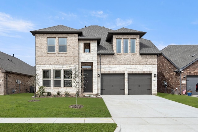 view of front of property featuring a shingled roof, concrete driveway, a front yard, a garage, and stone siding