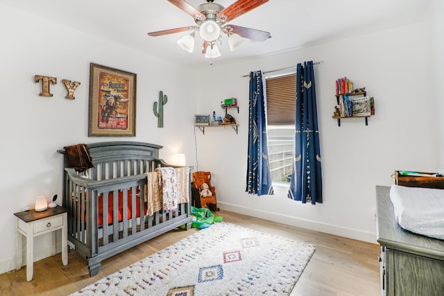 bedroom with ceiling fan, light hardwood / wood-style floors, and a crib