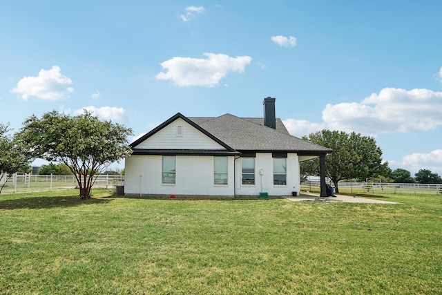 back of house with a yard and a rural view