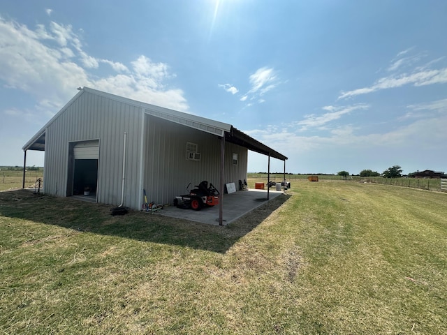 view of outbuilding with a lawn, a rural view, and a garage