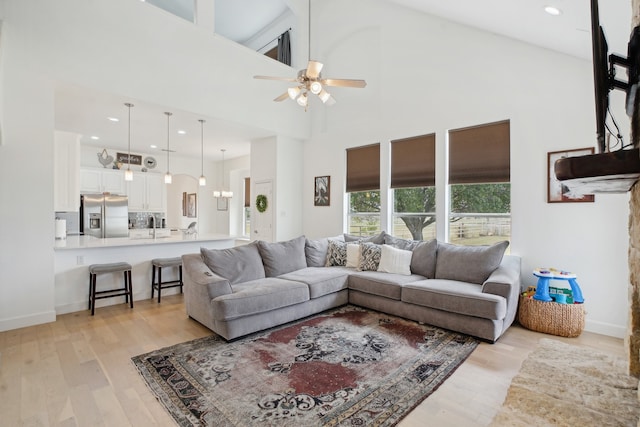 living room featuring ceiling fan, light hardwood / wood-style floors, and high vaulted ceiling