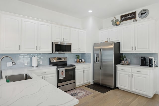 kitchen featuring tasteful backsplash, sink, white cabinets, and appliances with stainless steel finishes