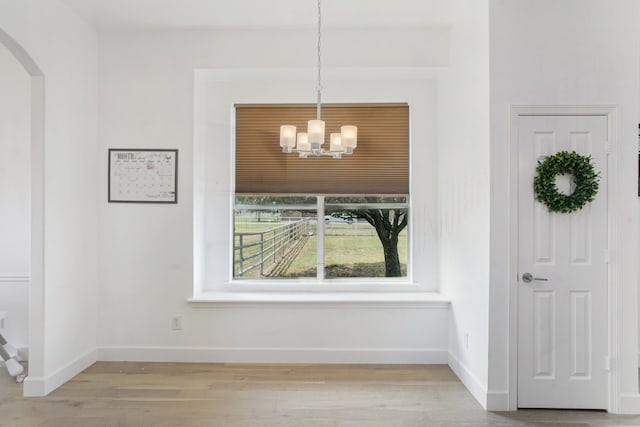 unfurnished dining area featuring a chandelier and light hardwood / wood-style floors