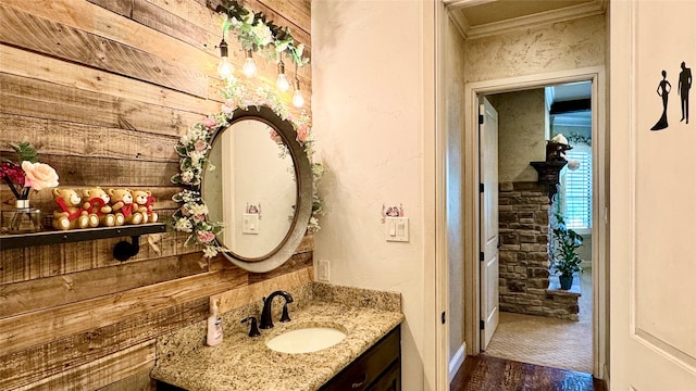 bathroom with hardwood / wood-style floors, vanity, crown molding, and wood walls