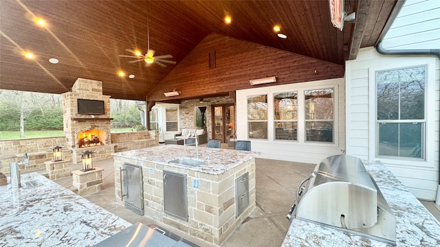 view of patio with area for grilling, sink, grilling area, and an outdoor stone fireplace