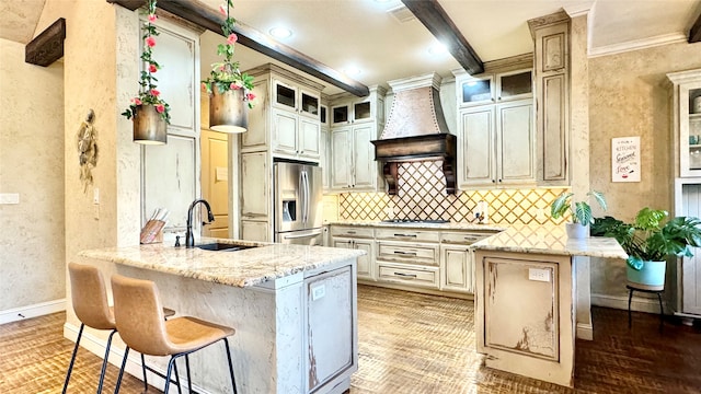 kitchen with kitchen peninsula, appliances with stainless steel finishes, a kitchen breakfast bar, light stone counters, and sink