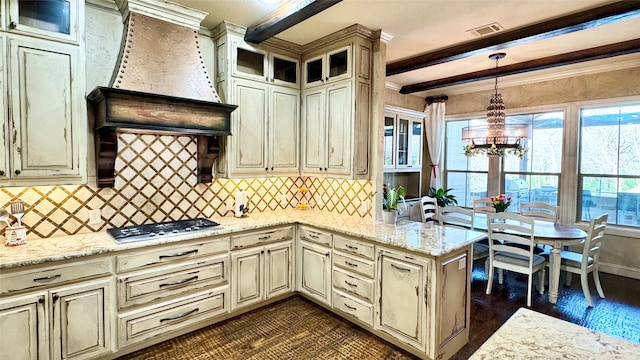 kitchen with stainless steel gas cooktop, beam ceiling, cream cabinets, decorative light fixtures, and an inviting chandelier