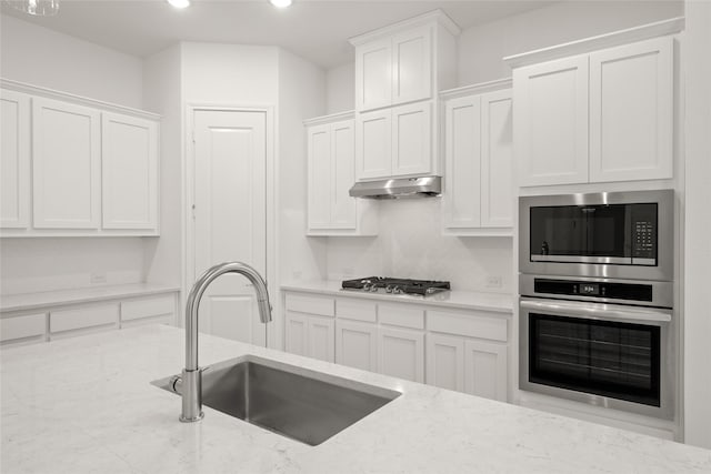 kitchen with a sink, stainless steel appliances, under cabinet range hood, and white cabinets