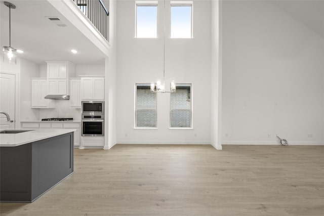 kitchen featuring a sink, decorative light fixtures, light wood-style floors, appliances with stainless steel finishes, and light countertops