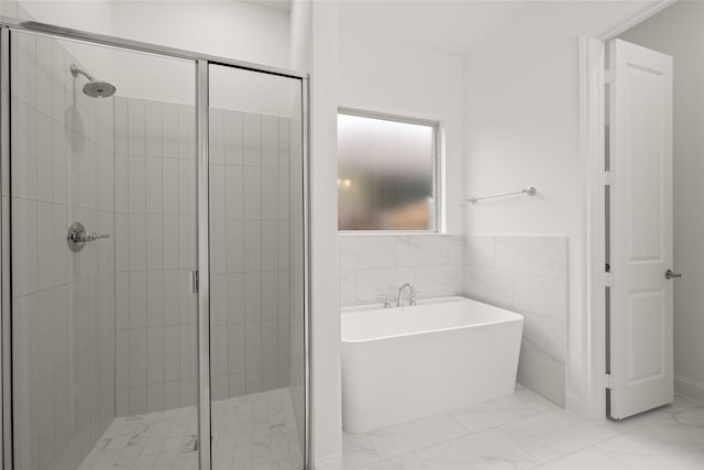 bathroom featuring a freestanding tub, tile walls, marble finish floor, and a stall shower