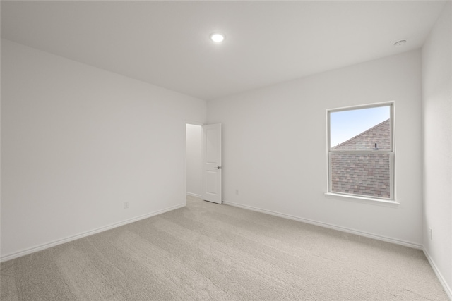 spare room featuring light carpet, recessed lighting, and baseboards