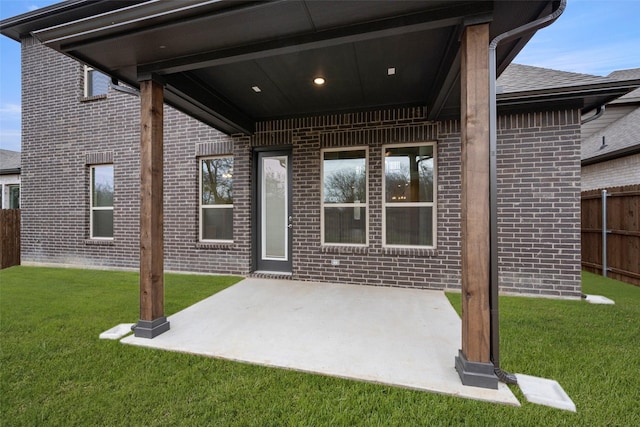 exterior space with a patio, a yard, fence, and brick siding