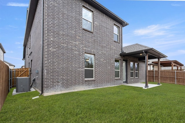 rear view of property featuring a patio, cooling unit, a lawn, and brick siding