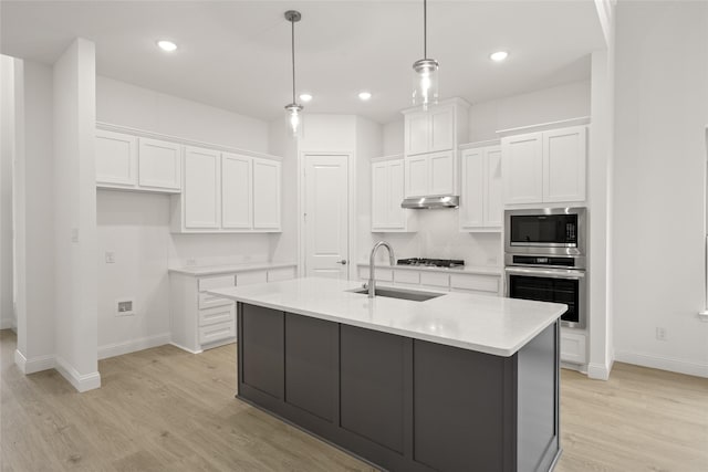 kitchen featuring oven, a sink, white cabinetry, light wood finished floors, and built in microwave