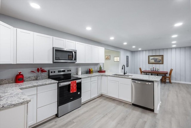 kitchen featuring sink, kitchen peninsula, stainless steel appliances, light hardwood / wood-style floors, and white cabinets