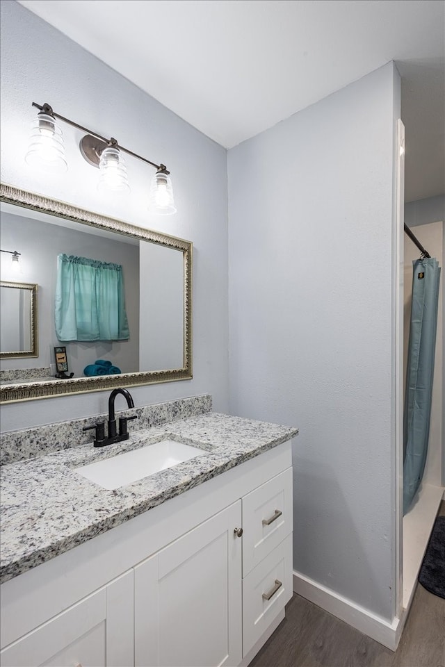 bathroom featuring walk in shower, vanity, and hardwood / wood-style flooring