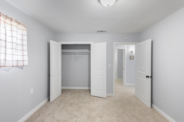 unfurnished bedroom featuring light carpet and a closet