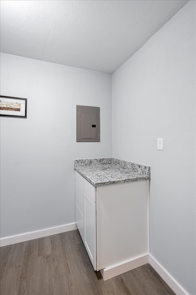 kitchen featuring light stone countertops, dark hardwood / wood-style flooring, electric panel, and white cabinetry