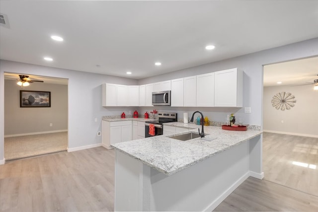 kitchen with sink, white cabinetry, light stone counters, kitchen peninsula, and stainless steel appliances