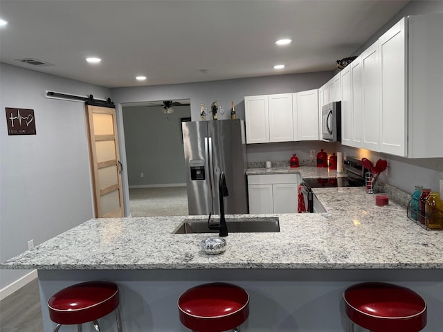 kitchen featuring a barn door, a breakfast bar area, appliances with stainless steel finishes, and a sink