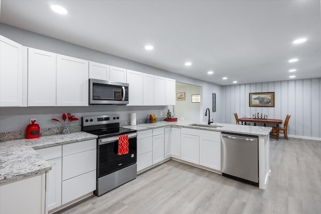 kitchen featuring white cabinetry, sink, stainless steel appliances, kitchen peninsula, and light hardwood / wood-style floors