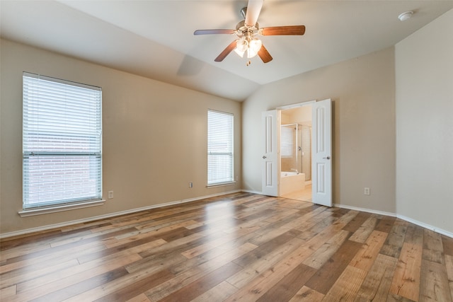 empty room featuring light hardwood / wood-style flooring, vaulted ceiling, plenty of natural light, and ceiling fan