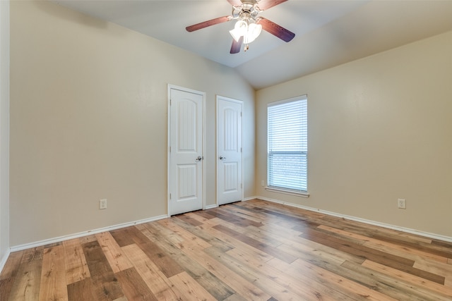 unfurnished bedroom with ceiling fan, multiple closets, light wood-type flooring, and vaulted ceiling